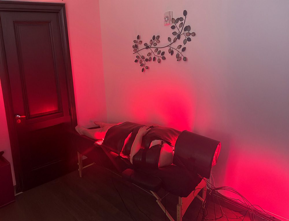 A massage table is set up in a room illuminated by soft red light, creating a calming atmosphere for relaxation.
